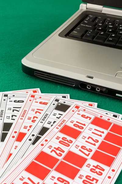 Bingo karty nad notebookem na zeleném pozadí — Stock fotografie