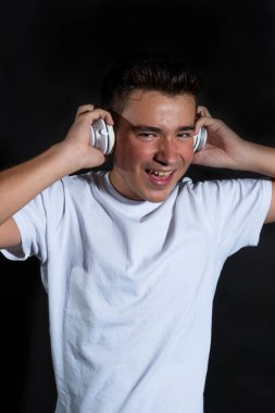 Beyazlar içinde, müzik dinleyerek müzik dinleyen, gülümseyen bir gencin portresi. KARANLIK Zemininde İZLENDİ.