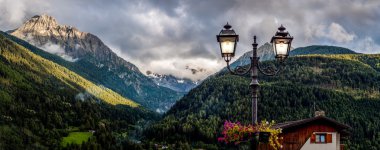 Lamp post in a mountain panorama with cloud and sun clipart