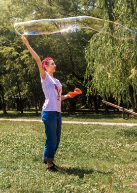 Mutlu genç kız kabarcıkları ile eğlenceli bir yaz günü parkta vardır