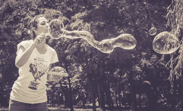 Счастливая девушка веселится с пузырями в летний день — стоковое фото