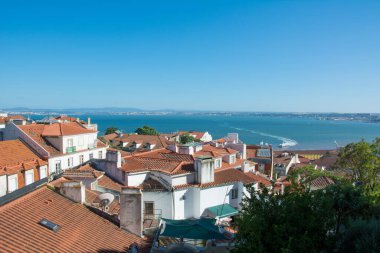 Lizbon ve Tagus Nehri manzarası sokaklar ve eski şehrin turuncu çatıları.