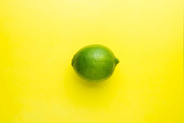 Fresh bright green lime on a yellow background.