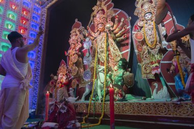 Howrah, Batı Bengal, Hindistan - 5 Ekim 2019: Hindu Bengali purohit Tanrıça Durga 'ya bir ayna gösteriyor, elbisesini bitirdikten sonra, Sondhya aarti gece renkli ışık altında çekim yapıyor..