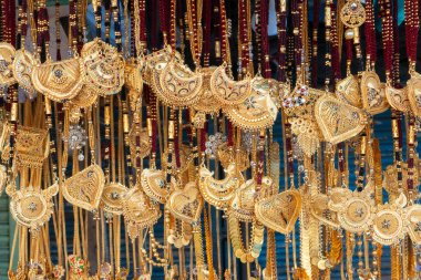 Hindistan 'da Kalighat, Kolkata, Batı Bengal' de, Hintli Bengalli kadınlara satılmak üzere uğurlu altın kaplama boyun parçaları asılıyor. Hinduizm 'de altın zenginliği simgeler. Hindu evli kadınlar bunları giyer..