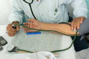 Kolkata, Batı Bengal, Hindistan - 25 Şubat 2018: Hintli Doktor, tıbbi aletleri olan bir hastanın kan basıncını kontrol ediyor.