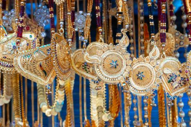 Hindistan 'da Kalighat, Kolkata, Batı Bengal' de, Hintli Bengalli kadınlara satılmak üzere uğurlu altın kaplama boyun parçaları asılıyor. Hinduizm 'de altın zenginliği simgeler. Hindu evli kadınlar bunları giyer..