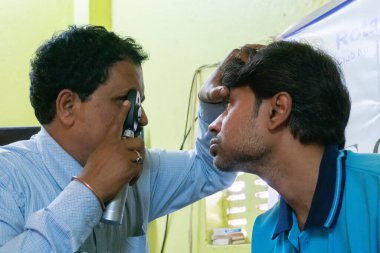 Kolkata, Batı Bengal, Hindistan - 25 Şubat 2018: Ücretsiz bir göz testi kampında genç bir adamın göz temasını kontrol eden erkek doktor. Editoryal stok resmi.