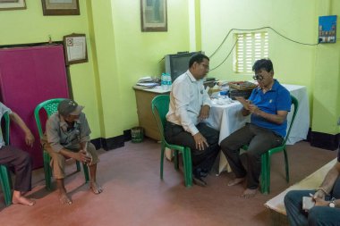 KOLKATA, INDIA - 19 Mart 2017: Ücretsiz bir göz testi kampında, bir sandalyede oturan yetişkin bir erkeğin göz görüşünü kontrol eden erkek doktor uzmanı. Editoryal stok resmi.