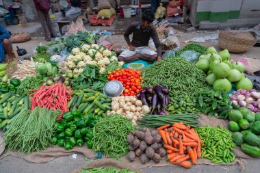 Kolkata, Batı Bengal, Hindistan - 16 Aralık 2018: Yol kenarı sebze pazarı. Territy Bazar, Kolkata 'da müşterilere satan genç bir adam..