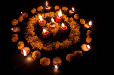 Yanlarına konmuş Rangoli çiçeklerinin, mumların ya da diyaların yan görüntüsü, geceleri Diwali ışıkları. Koyu arkaplan Stok resmi.