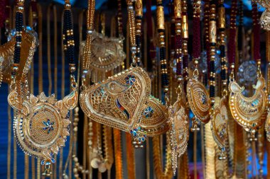 Hindistan 'da Kalighat, Kolkata, Batı Bengal' de, Hintli Bengalli kadınlara satılmak üzere uğurlu altın kaplama boyun parçaları asılıyor. Hinduizm 'de altın zenginliği simgeler. Hindu evli kadınlar bunları giyer..