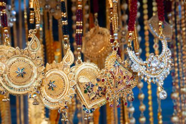 Hindistan 'da Kalighat, Kolkata, Batı Bengal' de, Hintli Bengalli kadınlara satılmak üzere uğurlu altın kaplama boyun parçaları asılıyor. Hinduizm 'de altın zenginliği simgeler. Hindu evli kadınlar bunları giyer..