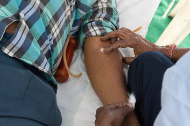 Kolkata, Batı Bengal, Hindistan - 25 Şubat 2018: Kamu kan bağışı kampında yatan genç bir erkek gönüllüden kan toplayan erkek hasta. Editoryal stok resmi.