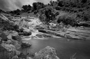 Güzel Ghatkhola şelalesi, Hindistan 'ın batısındaki Purulia kentindeki Ayodhya Pahar' da (tepe) yağmur nedeniyle taşların arasında yokuş aşağı akan tam akarsulara sahiptir. Siyah & Beyaz resim.