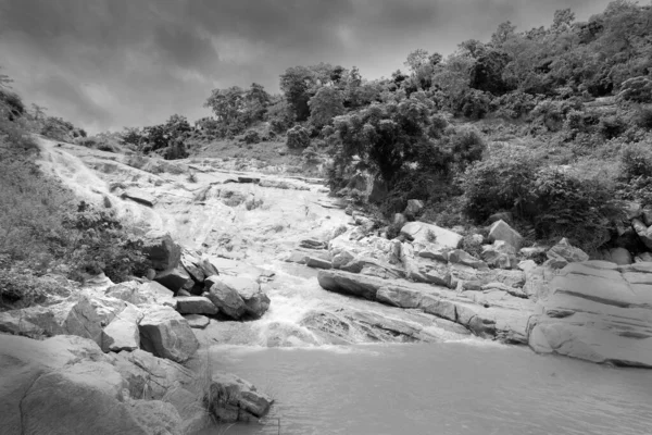 Beautiful Ghatkhola waterfall having full streams of water flowing downhill amongst stones , duriing monsoon due to rain at Ayodhya pahar (hill) - at Purulia, West Bengal, India. Black and White image.