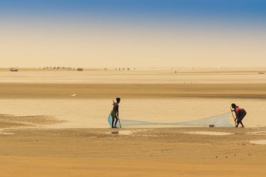 TAJPUR, Batı BEST BENGAL, INDIA - Haziran 22 ND, 2014: Bir balıkçının karısı ve oğlu sabah Bengal Körfezi kıyılarında balık ağıyla balık yakalıyor. Balıkçılık, Tajpur 'daki birçok insan için geçim kaynağıdır..