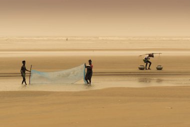 TAJPUR, Batı BEST BENGAL, INDIA - 22 Haziran 2014: Bengal Körfezi kıyılarında eşi ve oğluyla balık tutan bir balıkçı. Balıkçılık, Tajpur 'daki birçok kişi için geçim kaynağıdır..