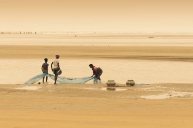 TAJPUR, Batı BEST BENGAL, INDIA - 22 Haziran 2014: Bengal Körfezi kıyılarında eşi ve oğluyla balık tutan bir balıkçı. Balıkçılık, Tajpur 'daki birçok kişi için geçim kaynağıdır..