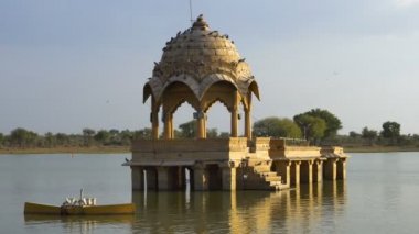Su kütlesi içindeki sarı taş yapılar, Jaisalmer şehrindeki Gadisar Gölü, su korunması için yapay olarak inşa edilmiştir. Jaisalmer, Rajasthan, Hindistan 'da öğleden sonra vuruldu.