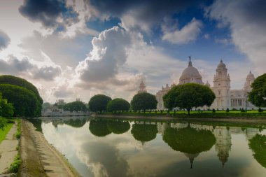 Kolkata, Batı Bengal, Hindistan - 28 Ağustos 2016: Mavi gökyüzü ve beyaz bulutlar ile Victoria Memorial ve su üzerinde yansıması. Çok ünlü bir Hint mimarisi tarihi anıtı..