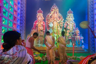 Howrah, Batı Bengal, Hindistan - 5 Ekim 2019: Hindu Bengalli bir kadın Sondhya aarti sırasında yüksek sesle shankha, deniz kabuğu kabuğu oynuyor. Dhaaks ve kansor ghonta tanrıça Durga 'ya tapmak için oynanır..