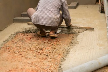 Hintli inşaat işçileri döşemeyi mala ve betona elle yapıştırıyorlar..