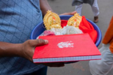 Tanrıça Laxmi 'nin renkli kil putlarını taşıyan genç adamın bulanık görüntüsü, Ganesha sembollü yeni hesap defteri, Kalighat, Bengali Yeni Yılı, Kolkata, Hindistan.