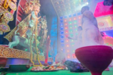 Durga Puja sırasında Durga dumanı altında tanrıça Durga 'ya tapan Hindu Bengalli rahiplerin bulanık görüntüsü. Durga aarti renkli ışığın altında çekildi.