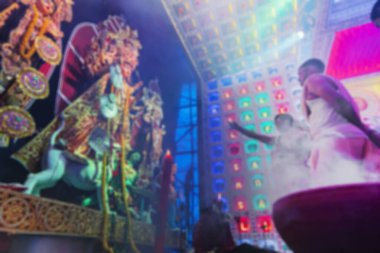 Durga Puja sırasında dumanla kaplanmış, tanrıça Durga 'ya tapan Hindu Bengalli rahiplerin bulanık görüntüsü. Aarti renkli ışığın altında vuruldu.