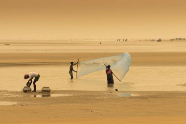 TAJPUR, Batı BEST BENGAL, INDIA - 22 Haziran 2014: Bengal Körfezi kıyılarında eşi ve oğluyla balık tutan bir balıkçı. Balıkçılık, Tajpur 'daki birçok kişi için geçim kaynağıdır..