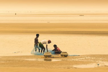 TAJPUR, Batı BEST BENGAL, INDIA - 22 Haziran 2014: Bengal Körfezi kıyılarında eşi ve oğluyla balık tutan bir balıkçı. Balıkçılık, Tajpur 'daki birçok kişi için geçim kaynağıdır..