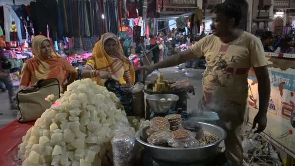 インド ラジャスタン州ジョードプル2019年10月21日 道路脇の販売店からラジャターニーの女性2人にペタなどのお菓子が販売されています — ストック動画