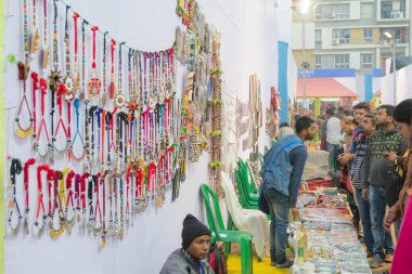 Kolkata, Batı Bengal, Hindistan - 31 Aralık 2018: Hintli adam müşterilere renkli el yapımı mücevherler satıyor, el sanatları satıyor. Hint el sanatları renkleriyle ünlüdür ve yaygın olarak kullanılır..