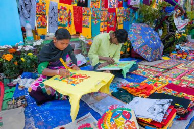 Kolkata, Batı Bengal, Hindistan - 31 Aralık 2018: Genç Bengalli kadın ve erkek sanatçılar Pattachitra veya Patachitra 'yı resmediyorlar - geleneksel, kumaş tabanlı parşömen resmi. El sanatları fuarında satılık..
