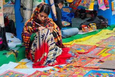Kolkata, Batı Bengal, Hindistan - 31 Aralık 2018: Genç Bengalli kadın ressam Pattachitra veya Patachitra - geleneksel kumaş tabanlı parşömen tablosu. El sanatları fuarında satılık..