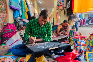 Kolkata, Batı Bengal, Hindistan - 31 Aralık 2018: Pattachitra veya Patachitra 'yı resmeden genç Bengalli erkek ve kadın sanatçılar - geleneksel kumaş tabanlı parşömen resmi. El sanatları fuarında satılık..