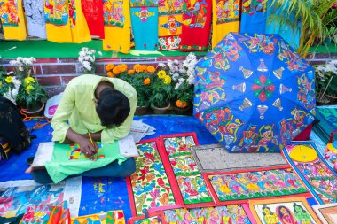 Kolkata, Batı Bengal, Hindistan - 31 Aralık 2018: Genç Bengalli ressam Pattachitra veya Patachitra - geleneksel kumaş tabanlı parşömen tablosu. El sanatları fuarında satılık..