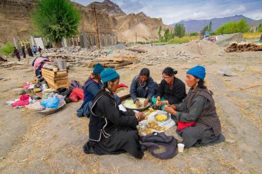 Mulbekh, Ladakh, Hindistan - 2 Eylül 2014: Geleneksel elbiseli Ladakhi kabile kadınları arka planda Himalaya dağları, dini festival için sebze kesiyor.