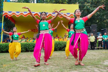 Kolkata, Batı Bengal, Hindistan - 9 Mart 2020: Renkli Hint elbiseleri giymiş, Dol utsab veya Holi festivalinde dans eden gülümseyen genç Bengalli kız dansçılar. Hindistan 'da bahar kutlaması.