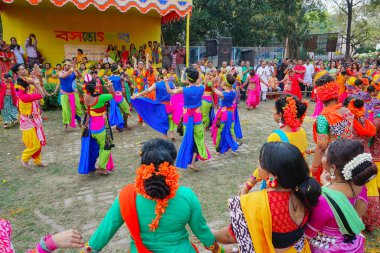 Kolkata, Hindistan - 9 Mart 2020: Renkli sari (geleneksel Hint elbisesi) giymiş kız dansçılar ve Palash çiçekleri (Butea monosperma) makyaj, Dol (Bengalce) veya Holi (Hintçe) festivalinde dans.