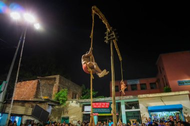 Howrah, Batı Bengal, Hindistan - 15 Nisan 2019: İki Hindu fanatiği gece direğe asılıyor. Tanrı Shiva-Hindu 'ya tapınmanın bir parçası olan Charhak ya da Gajan adlı festival için dini sporlar.