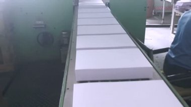 Paket kağıdı paketleme makinesi çalışıyor. A4 boyutunda beyaz fotokopi makinesi ya da fotokopi kağıdı kesiliyor, istifleniyor, sayılıyor ve son paketleme için el ilanları gönderiliyor ve sonra pazara satılıyor..