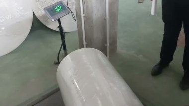 Technician checking the weight of a paper reel before putting it on a paper printing machine. Shot at Kolkata, West Bengal, India.