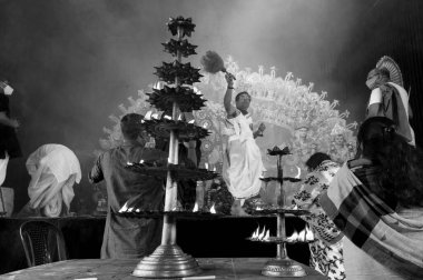 Howrah, Batı Bengal, Hindistan - 25 Ekim 2020: Hindu rahip Durga 'ya kutsal dumanla sondhipujo aarti sırasında kutsal panchapradip ile tapıyor. Shonkho oynuyor. B&W.