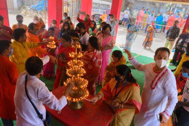 Howrah, Batı Bengal, Hindistan - 25 Ekim 2020: Hindu rahip tanrıça Durga 'ya tapıyor. Kutsal panchapradip, maskeli Hindu fanatikler tarafından sondhipujo aarti sırasında yakılıyor. Puja salgında..