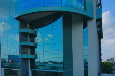 Kolkata, Batı Bengal, Hindistan - 20 Temmuz 2019: Binaların modern mimarisi, cam dış görünüş mavi gökyüzünü, beyaz bulutları ve binaları yansıtıyor.