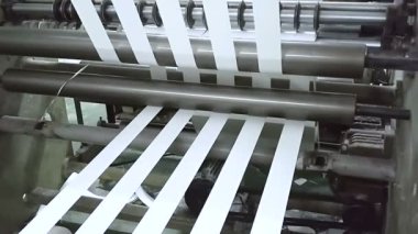 Kâğıt makaralarından kağıt rulo kesiliyor, kağıt bardakların temelini oluşturduğu için. Çalışan bir bardak imalat ya da üretim ünitesinin görüntüsü.