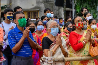 Howrah, Batı Bengal, Hindistan - 25 Ekim 2020: Sanskrit shlokas 'ı tanrıça Durga' ya iten maskeli kadın dindarlar. Ashtami sabahı, Coronavirus salgınında Durga puja festivali.