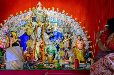 Howrah, Batı Bengal, Hindistan - 24 Ekim 2020: Maskeli Hindu dindar kadın deniz kabuğu çalarken tanrıça Durga Hindu rahipler tarafından tapınılıyor. Coronavirüs salgınında Puja.